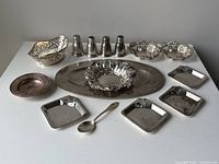 Overview of entire lot on white surface: tray, bowl, baskets, shakers, dishes, spoon