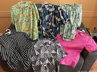 Overview of six men’s Hawaiian-style shirts laid out on sofa