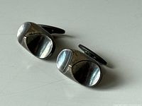 Pair of sterling silver Georg Jensen vintage cufflinks showing one side with curved indented oval faces and visible wear and tarnish.
