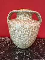 Front-left angled view of mottled brown, cream, and gold vase showing double handles and rounded shape