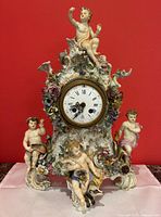 Full-frontal view showing overall clock with four cherub figures, floral garlands and scroll base against red background