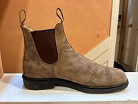 Side view of single boot showing rustic brown leather and elastic panel