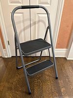 Full view of metal step ladder angled showing two steps and handle padding.