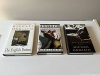 Photo of three hardcover Michael Ondaatje novels: The English Patient, In the Skin of a Lion, and Divisadero, showing all front covers.