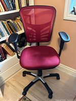 Front view of ergonomic office chair with red mesh back and red cushioned seat, black adjustable armrests, and five-star caster base with silver accent.