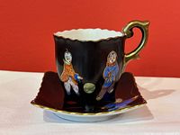 Porcelain demitasse cup and square saucer with matte black glaze, hand-painted children figures and gold trim