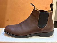 Right side view of one boot on white surface against orange background