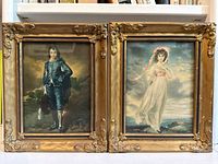 Pair of vintage ornate framed prints showing Blue Boy and Pinkie side by side with visible cracks and chips to frames.