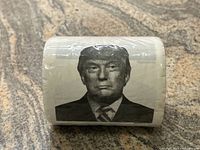 Photo showing the full front of the rolled novelty toilet paper depicting a black and white image of Donald Trump.