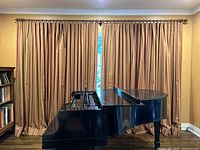 Full view of the striped drapes closed with the wooden rod across the top, shown with a black grand piano in front.