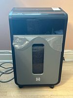 Front view showing full shredder with transparent bin window and plastic liner inside bin