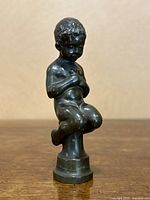 Front view of bronze boy sculpture on wooden table