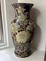 Front view of large vintage ceramic floral vase with dark brown glaze and raised decorations.