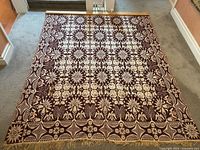 Full view of tapestry laid flat on floor showing overall pattern and fringe