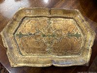 Top view of octagonal gilt tray showing detailed floral decoration and wear on gold leaf.