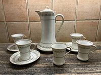 Full set arranged on countertop including pitcher, cups and saucers showing patterns and scale.