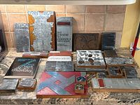 Wide shot showing all metal printing plates arranged on counter with three books on the left side.