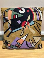 Front view of the embroidered throw pillow showing abstract modern art design with vibrant multicolor threadwork on mustard dyed fabric.