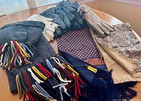 Overall lot showing five pairs of gloves in various colors and types, and four scarves including knit and silk types spread on a table
