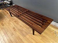 Three-quarter front view showing slatted top and leg construction