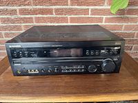 Front view of black Pioneer VSX-D557 receiver showing all front panel controls, digital display, input knobs, and volume dial on wooden surface.