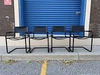 Front view of four black leather cantilever chairs in a row