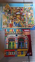 Two puzzle boxes: Ravensburger The Bizarre Bookshop No.2 and Sure-Lox colorful building facade, both labeled 1000 pieces