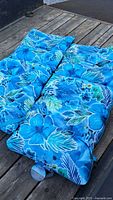 Pair of blue floral patio cushions on wooden surface