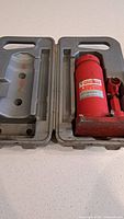 Bottle jack seated in open grey plastic case