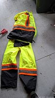 Two-piece high-visibility rain suit laid out showing jacket and pants