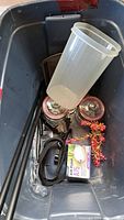 Bin containing curtain rod sections, glass canisters, plastic container, leash, air pump box, aquarium plant, baking pan