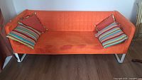 full view of orange sofa with pillows