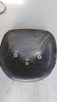 top view of black vinyl tractor seat showing cushion and three mounting grommets