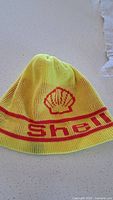 Front view of yellow Shell knit beanie showing logo and stripe