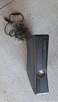 Xbox 360 console with wired controller beside it