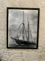 Framed black and white photo art of blue nose sail boat on water in a black frame