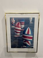 Framed art print showing British sailboats with distinct red, white, and blue sails on the water, inside a gold-tone frame with matting.