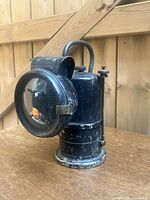 Side angle of the right front black metal oil lamp showing wear and glass lens