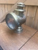 Side view of the antique Neverout brass lamp showing the body, glass front, and vented top.