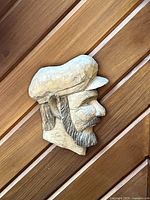 Side profile image of the hand-carved wooden sailor head wall art mounted on a wooden background showing detailed carving and texture.