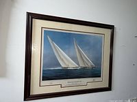 Framed art print showing two sailing yachts racing, signed by Tim Thompson, mounted and framed in dark wood.