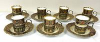Seven complete demitasse cup sets with saucers and sterling holders displayed
