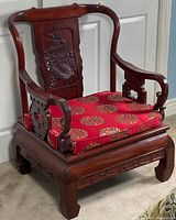 Front angle view showing carved dragon backrest, lattice arm, cushion, and leg relief