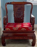 Front view of armchair showing crest rail, dragon back splat, carved apron and cushion