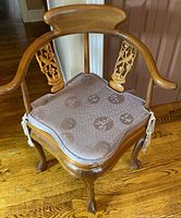 Front angled view showing overall chair, curved back, carved splat, cushion