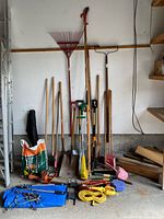 Group shot of long-handled garden tools, bag of soil, and string trimmer