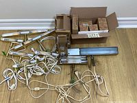 Group of brass picture lights with cords, one metal art light, boxes of bulbs