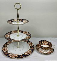 Full view of assembled three-tier cake stand alongside matching teacup and saucer