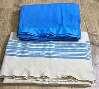 Folded blue Kenwood blanket stacked on cream striped blanket