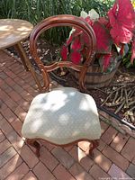 Front three-quarter view of chair showing balloon back, carvings, upholstered seat